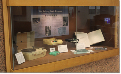 Exhibit case with the Talking Book Program display of various play-back machines plus large-print and Braille books available for Texans who are unable to read regular books.